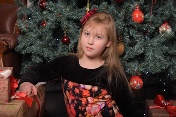 girl blonde child in black with red dress in christmas by the christmas tree