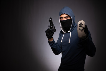 Young gangster in hood on grey background 