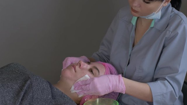 Doctor cosmetologist makes Rejuvenating facial pilling procedure for tightening and smoothing wrinkles on face skin of beautiful, young woman in beauty salon.Cosmetology skin care.