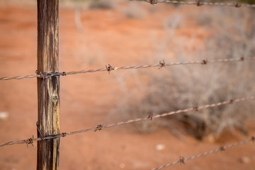 Rusty barb wire fence and old wood poles on Kalahari red sand farm