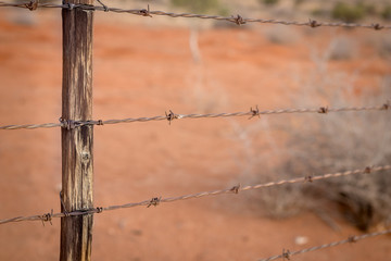 Rusty barb wire fence and old wood poles on Kalahari red sand farm