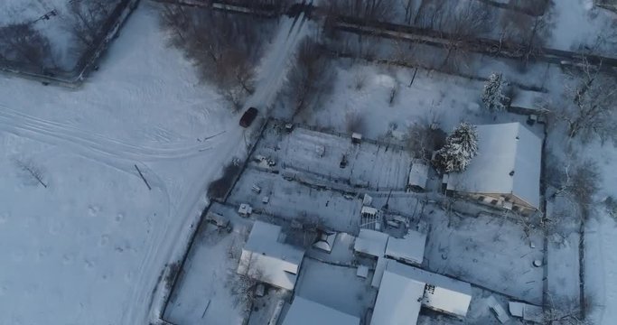 (original 4k file) SUV shot from a drone moves among the snow-covered roofs of private houses
