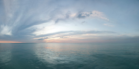 Colorful seascape. Twilight sunset over the sea with colorful clouds. Panorama of cloudy sky and aqua water