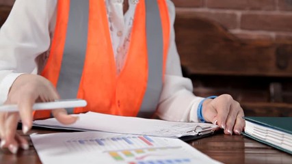 Young female engineer takes notes on work.Special uniform and helmet