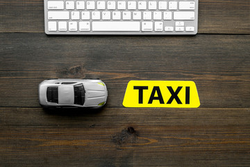 Choose, select taxi concept. Order taxi online. Sign ner car toy and keyboard on dark wooden...