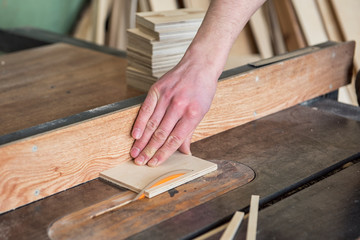 Construction worker cutting wooden board with circular saw