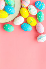 Fototapeta na wymiar Festive Easter table. Colorful Easter eggs on plate on pink background top view space for text