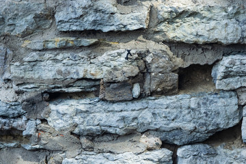 Old grey rough stone wall close-up texture background, selective focus, shallow DOF