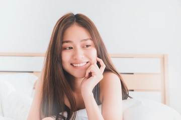 Young Asian beautiful woman smiling and relax on bed in bedroom.Health and beauty woman concept.