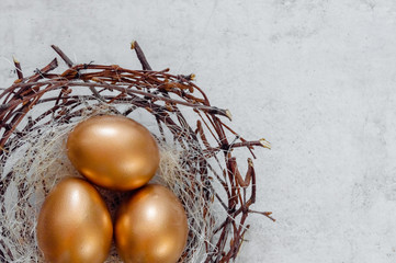 Fototapeta premium Golden Easter Eggs in birds Nest over rustic background. Easter Holiday concept abstract background copyspace top view several objects.Close up view