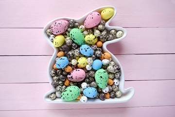 Easter concept.Easter bunny   with Easter speckled eggs on a light pink wooden board background.Easter Flat lay. top view, copy space.