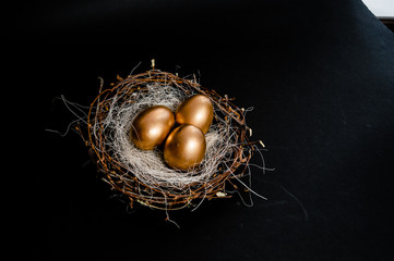 Naklejka na ściany i meble Golden Easter Eggs in birds Nest on black background. Easter Holiday concept abstract background copyspace top view several objects.