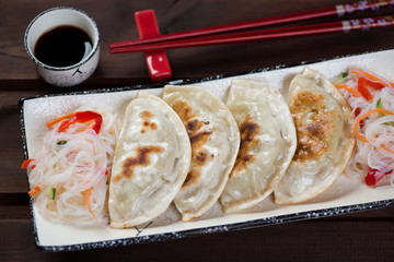 Closeup of pan fried korean potstickers with funchoza noodles salad on a plate