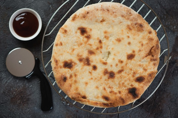 Above view of ossetian pie with chicken and cheese stuffing on a metal cooling rack, horizontal shot