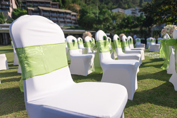 wedding chairs that cover with white cloth and decorate with soft green cloth for guest in ceremony