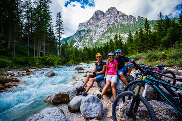Tourist cycling in Cortina d'Ampezzo, stunning rocky mountains on the background. Family riding MTB...