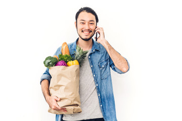 Man holding shopping paper bag with fruit and vegetables on white background