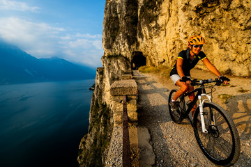 Cycling woman  riding on bikes at sunrise mountains and Garda lake landscape.  Cycling MTB enduro...
