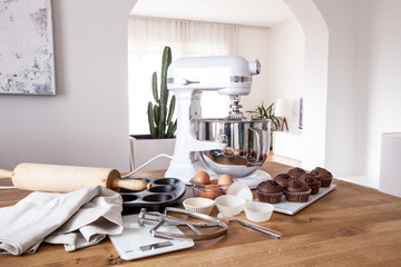 White kitchen machine and stand mixer on a wooden table in a bright design apartment