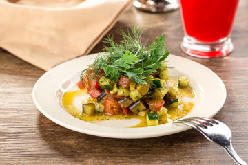 Grilled vegetables warm salad with zucchini, eggplant, onions, peppers and tomato with berry juice on wooden table