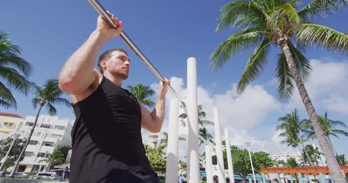 Fitness man doing pull ups chest to bar training working out muscles at outdoor gy.