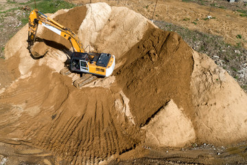 Tracked excavator overloads the sand from the embankment