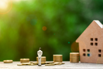 Miniature businessman figure standing for see the future front a golden coins. - Finance and loan, saving money for a retirement in the future concepts.