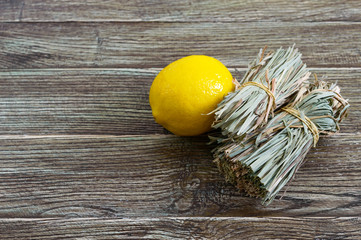 Organic dry lemongrass (Cymbopogon flexuosus) in bunches and lemon fruit on a wooden table. Herbs for tea.
