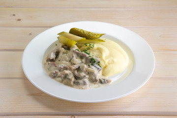Goulash with mashed potato and pickled cucumber