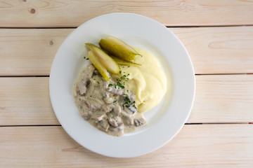Goulash with mashed potato and pickled cucumber