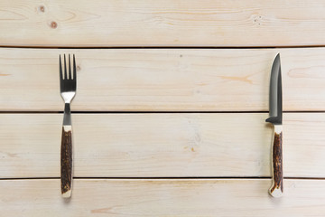 Overhead view of tourist knife and fork with horn handle on empty wooden table