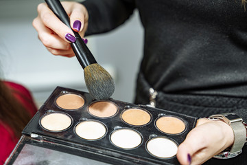 Female makeup artist with cosmetics at work close-up