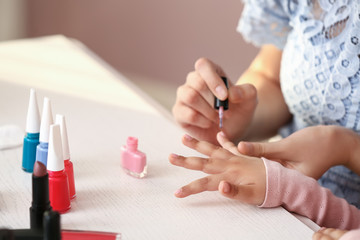 Obraz na płótnie Canvas Cute daughter with mother making manicure at home