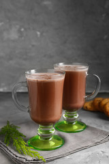 Glass cups of hot cacao drink on grey table