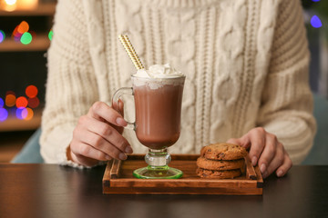Young woman drinking tasty cacao with cookies in cafe