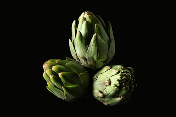 Fototapeta premium Raw artichokes on black background