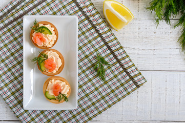 Tartlets with cream cheese and salted salmon on a white plate. Tasty light snack for a party. Finger Food. The top view, flat lay.