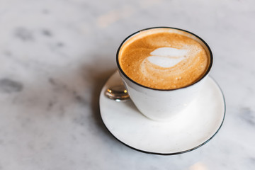 A cup of coffee with latte art in the coffee shop.