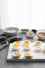 Hard-boiled cut eggs with ingredients on table