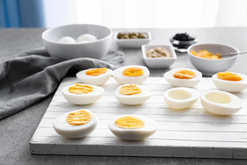 Hard-boiled cut eggs with ingredients on table