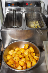 Deep fryer and fried potatoes with slices of rustic in a restaurant, kitchen
