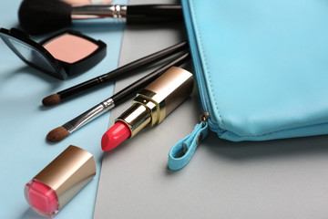 Bag with professional makeup cosmetics on color background