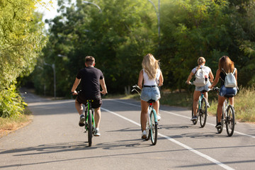 three girls and one guy ride bicycles outdoors, outdoor activities, lifestyle, concept of sport