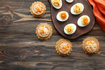 Tasty deviled eggs with tartlets on wooden table