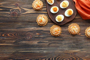 Tasty deviled eggs with tartlets on wooden table