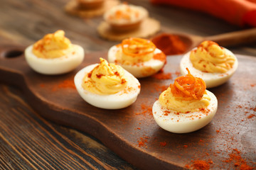 Tasty deviled eggs on wooden board, closeup