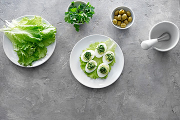 Plate with tasty deviled eggs and products on grey table