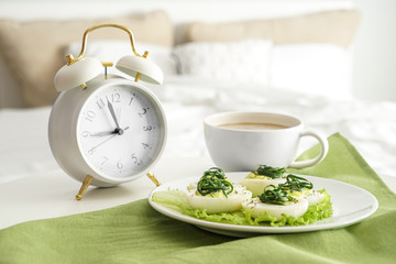 Plate with tasty deviled eggs and cup of coffee on bed