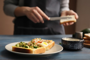 Plate with tasty avocado sandwiches on wooden table