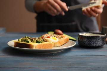 Plate with tasty avocado sandwiches on wooden table